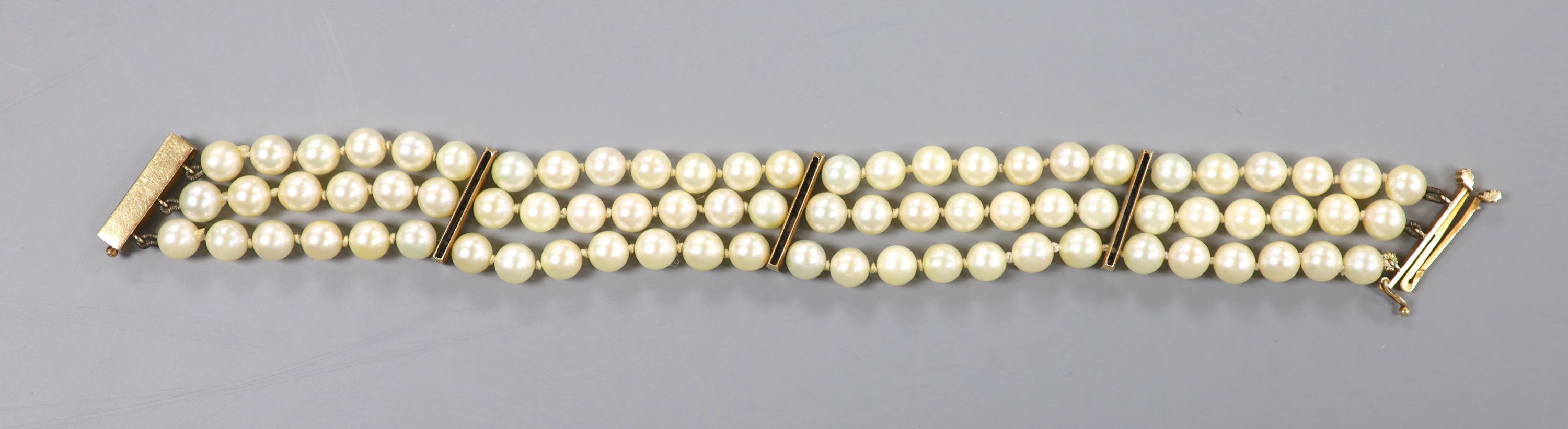 A triple strand cultured pearl bracelet, with yellow metal and diamond chip set spacers and clasp, 20.5cm, gross weight 34.2 grams, pearl diameter 6.4mm.